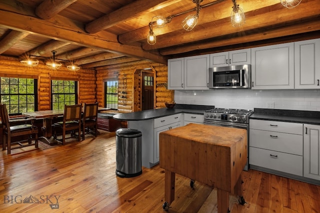 25 Big Chief Trl, Bozeman, MT 59718 - kitchen featuring stainless steel appliances, a wood ceiling with exposed beams, a peninsula, dark countertops, and log walls