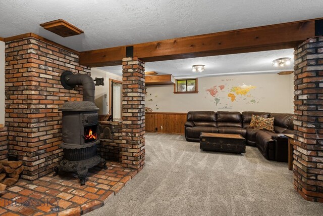 25 Big Chief Trl, Bozeman, MT 59718 - carpeted living room featuring a textured ceiling, wooden walls, a wainscoted wall, and a wood stove