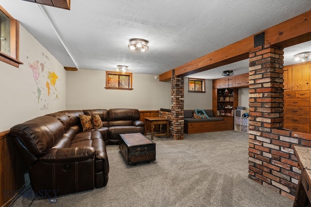 25 Big Chief Trl, Bozeman, MT 59718 - carpeted living room featuring ornate columns, a textured ceiling, wainscoting, wooden walls, and beamed ceiling