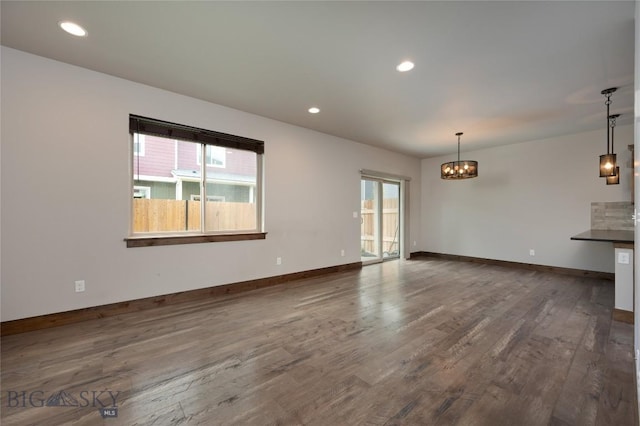 1304 Glider Ln Unit B, Belgrade, MT 59714 - unfurnished living room featuring dark wood-style floors, a chandelier, baseboards, and recessed lighting