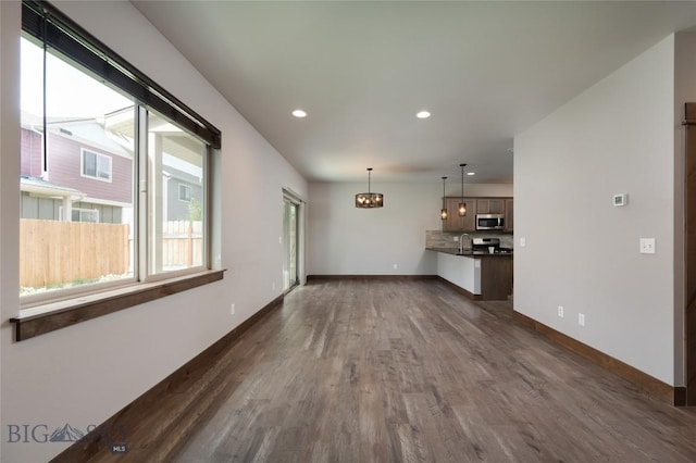 1304 Glider Ln Unit B, Belgrade, MT 59714 - unfurnished living room with dark wood-style floors, a chandelier, recessed lighting, baseboards, and a sink