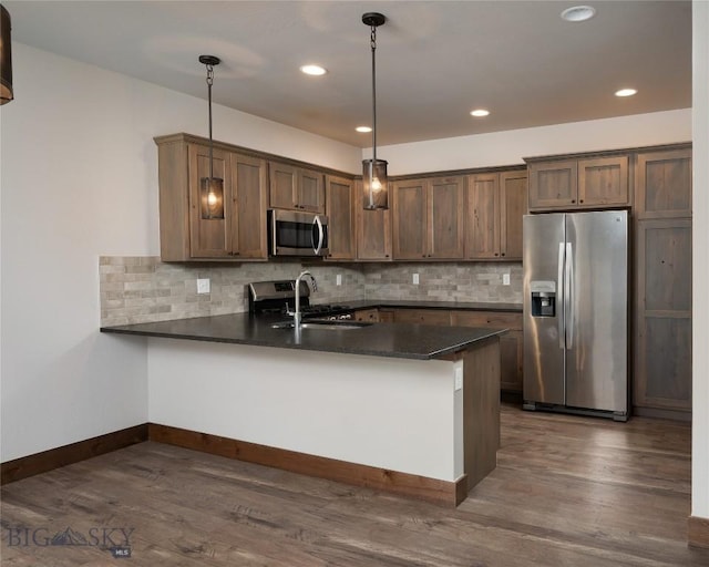 1304 Glider Ln Unit B, Belgrade, MT 59714 - kitchen with stainless steel appliances, dark countertops, a peninsula, tasteful backsplash, and recessed lighting