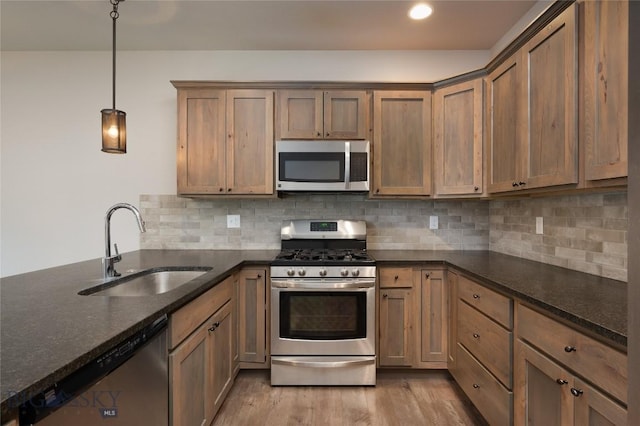 1304 Glider Ln Unit B, Belgrade, MT 59714 - kitchen with appliances with stainless steel finishes, a sink, light wood-style flooring, dark stone counters, and tasteful backsplash