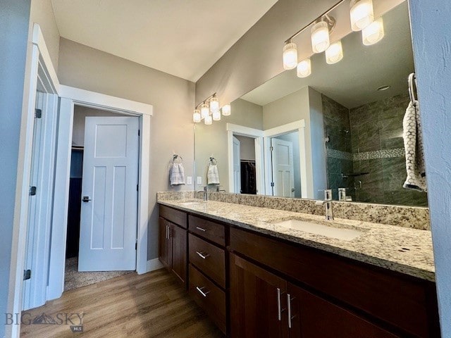 920 Butler Creek Ave, Belgrade, MT 59714 - bathroom with wood finished floors, a tile shower, a spacious closet, double vanity, and baseboards