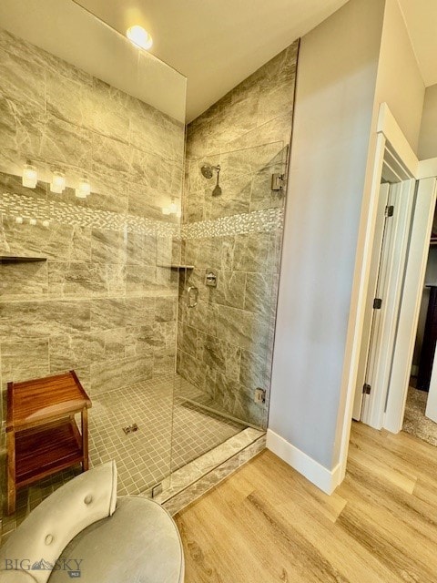 920 Butler Creek Ave, Belgrade, MT 59714 - bathroom featuring tiled shower, wood finished floors, and baseboards