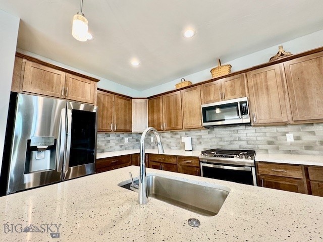 920 Butler Creek Ave, Belgrade, MT 59714 - kitchen with stainless steel appliances, a sink, light stone countertops, brown cabinets, and backsplash