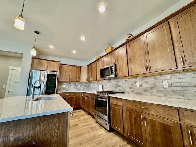 920 Butler Creek Ave, Belgrade, MT 59714 - kitchen with stainless steel appliances, brown cabinets, decorative light fixtures, light stone counters, and light wood-type flooring
