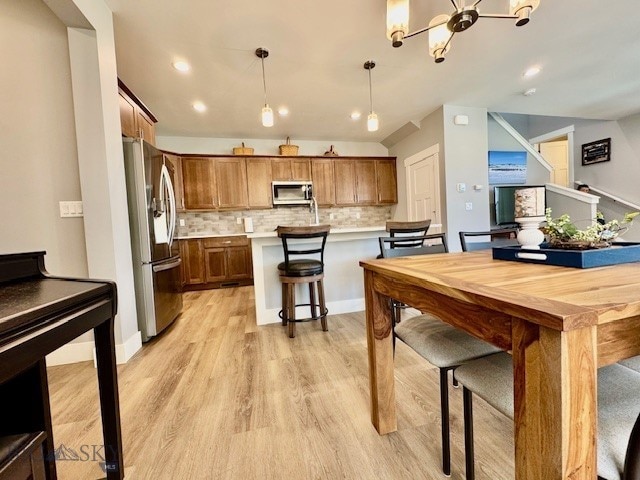 920 Butler Creek Ave, Belgrade, MT 59714 - kitchen with stainless steel appliances, light countertops, light wood-type flooring, tasteful backsplash, and brown cabinets