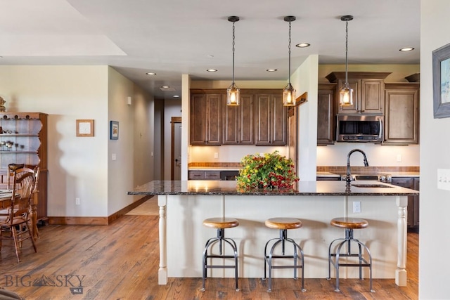 43 Lewis Dr, Three Forks, MT 59752 - kitchen featuring stainless steel microwave, a sink, a kitchen breakfast bar, baseboards, and a center island with sink