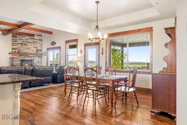 43 Lewis Dr, Three Forks, MT 59752 - dining space with wood finished floors, a stone fireplace, a raised ceiling, a chandelier, and beam ceiling