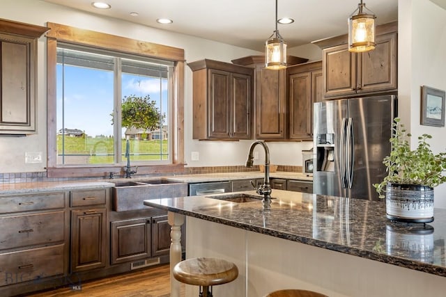 43 Lewis Dr, Three Forks, MT 59752 - kitchen with stainless steel fridge with ice dispenser, a sink, dark stone countertops, a breakfast bar area, and recessed lighting
