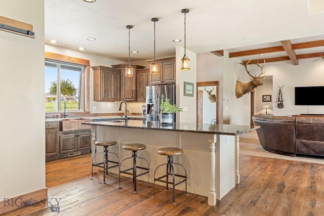 43 Lewis Dr, Three Forks, MT 59752 - kitchen with stainless steel fridge with ice dispenser, a kitchen bar, hardwood / wood-style flooring, beam ceiling, and a kitchen island with sink