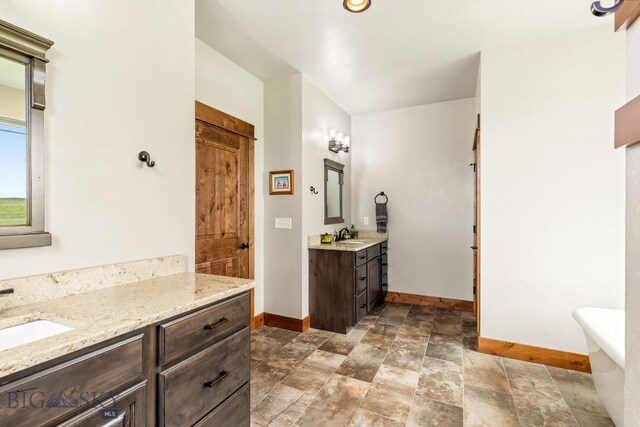 43 Lewis Dr, Three Forks, MT 59752 - full bathroom featuring baseboards, stone finish flooring, two vanities, and a freestanding tub