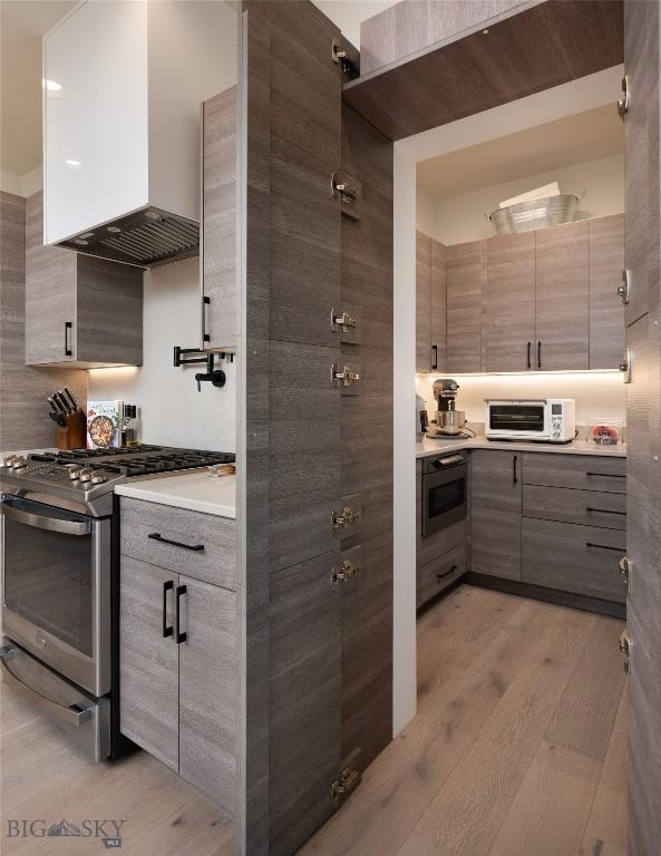 1510 Windrow Dr, Bozeman, MT 59718 - kitchen featuring gas stove, light wood finished floors, wall chimney range hood, modern cabinets, and oven