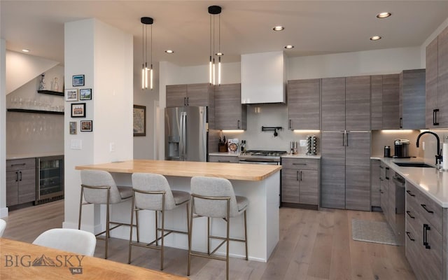 1510 Windrow Dr, Bozeman, MT 59718 - kitchen featuring appliances with stainless steel finishes, a sink, beverage cooler, a kitchen bar, and light wood-type flooring