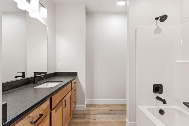 608 Spaniel Ln, Belgrade, MT 59714 - full bathroom featuring wood finished floors, vanity, baseboards, and shower / washtub combination