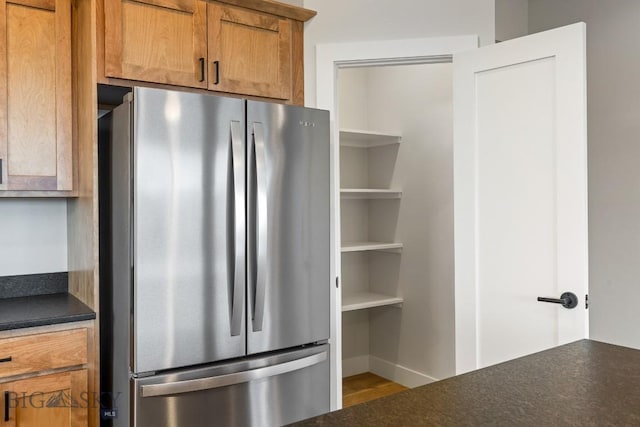 608 Spaniel Ln, Belgrade, MT 59714 - kitchen with freestanding refrigerator, dark countertops, brown cabinets, wood finished floors, and baseboards
