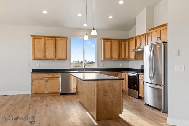 608 Spaniel Ln, Belgrade, MT 59714 - kitchen with appliances with stainless steel finishes, under cabinet range hood, dark countertops, a center island, and light wood-style floors