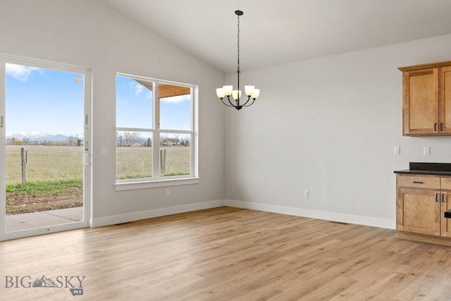 608 Spaniel Ln, Belgrade, MT 59714 - unfurnished dining area with a chandelier, light wood-style floors, lofted ceiling, and baseboards