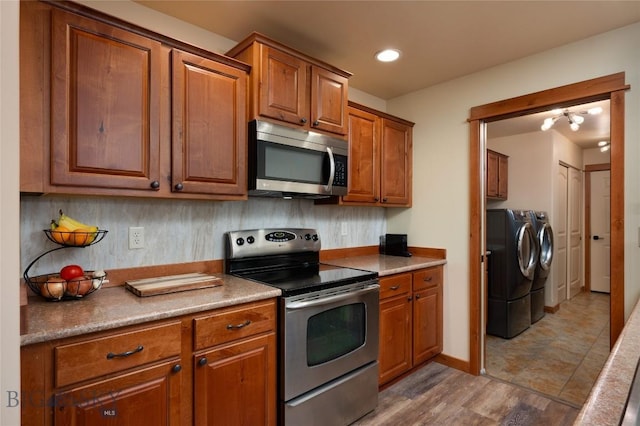 1079 N Cottonwood Rd, Bozeman, MT 59718 - kitchen with stainless steel appliances, washing machine and dryer, brown cabinetry, and recessed lighting