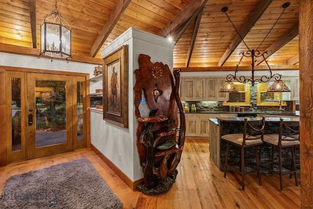14585 Eagle Eye Way, Gallatin Gateway, MT 59730 - kitchen with wood ceiling with exposed beams, dark countertops, light wood-style floors, a kitchen breakfast bar, and tasteful backsplash