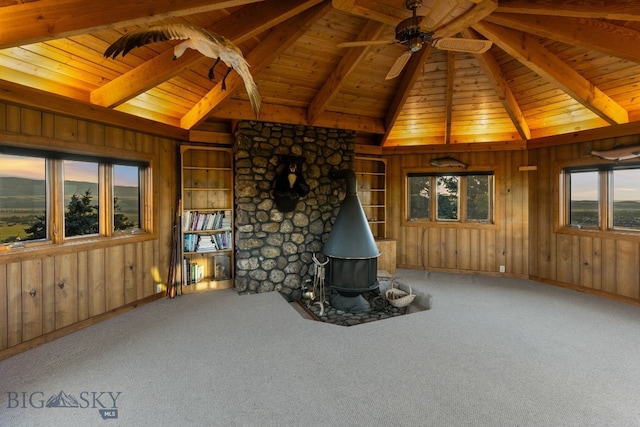 14585 Eagle Eye Way, Gallatin Gateway, MT 59730 - unfurnished living room with a wood stove, wooden walls, a ceiling fan, carpet floors, and wooden ceiling