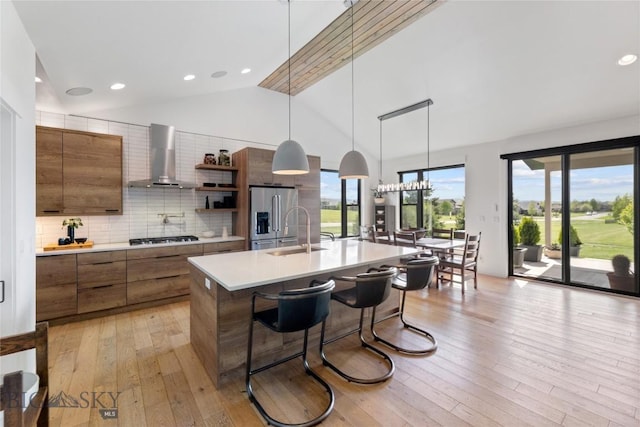 646 Arrow Trl, Bozeman, MT 59718 - kitchen with wall chimney range hood, stainless steel appliances, light countertops, a sink, and brown cabinetry