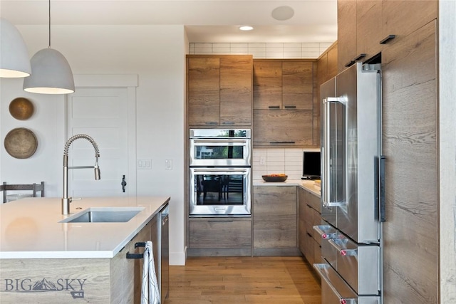 646 Arrow Trl, Bozeman, MT 59718 - kitchen featuring stainless steel appliances, a sink, brown cabinets, light countertops, and light wood-style floors