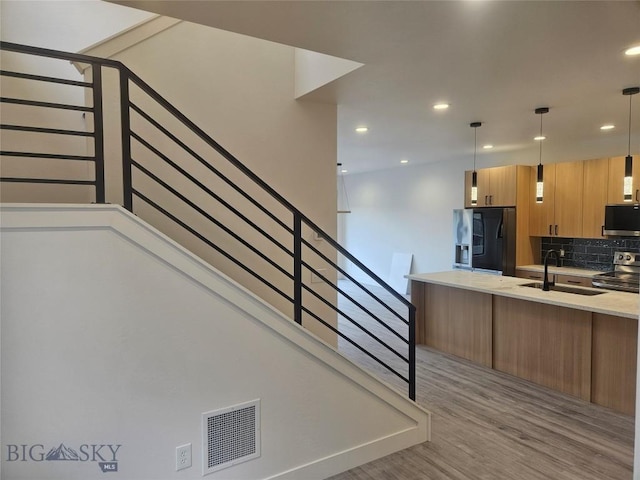 1102 Ridgeview Trl, Livingston, MT 59047 - kitchen featuring black refrigerator with ice dispenser, stainless steel electric stove, a sink, light wood finished floors, and decorative backsplash