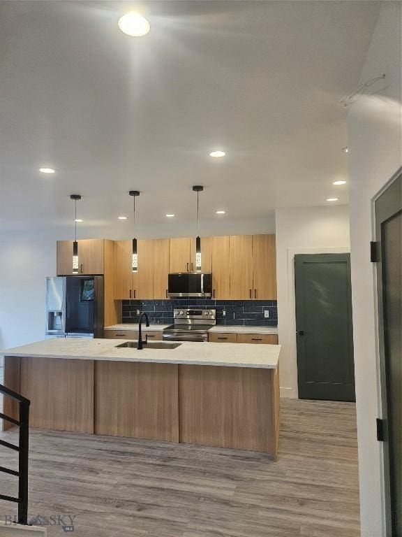1102 Ridgeview Trl, Livingston, MT 59047 - kitchen with appliances with stainless steel finishes, light countertops, backsplash, a large island with sink, and light wood-style flooring