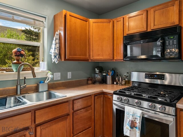 1009 Wyoming St, Belgrade, MT 59714 - kitchen with gas range, black microwave, light countertops, and brown cabinetry