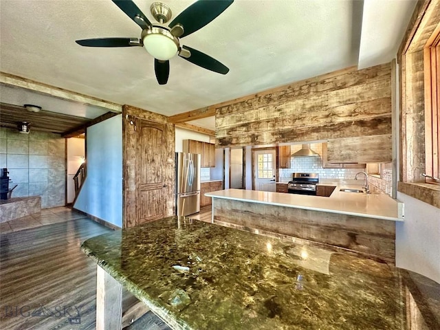 400 Broken Creek Rd, Three Forks, MT 59752 - kitchen featuring appliances with stainless steel finishes, wall chimney range hood, a sink, a ceiling fan, and a peninsula