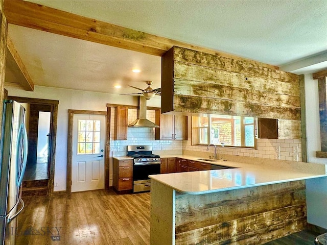 400 Broken Creek Rd, Three Forks, MT 59752 - kitchen featuring appliances with stainless steel finishes, wall chimney range hood, a sink, a peninsula, and decorative backsplash