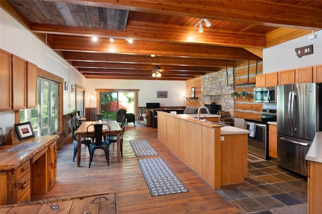 495 Jardine Rd, Gardiner, MT 59030 - kitchen featuring appliances with stainless steel finishes, track lighting, open floor plan, an island with sink, and a stone fireplace
