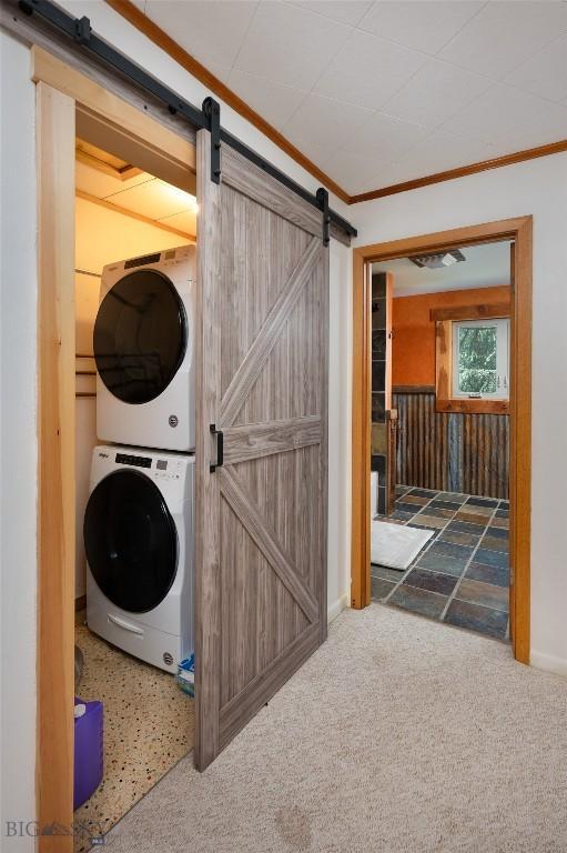 495 Jardine Rd, Gardiner, MT 59030 - laundry area featuring stacked washing machine and dryer, a barn door, ornamental molding, and carpet