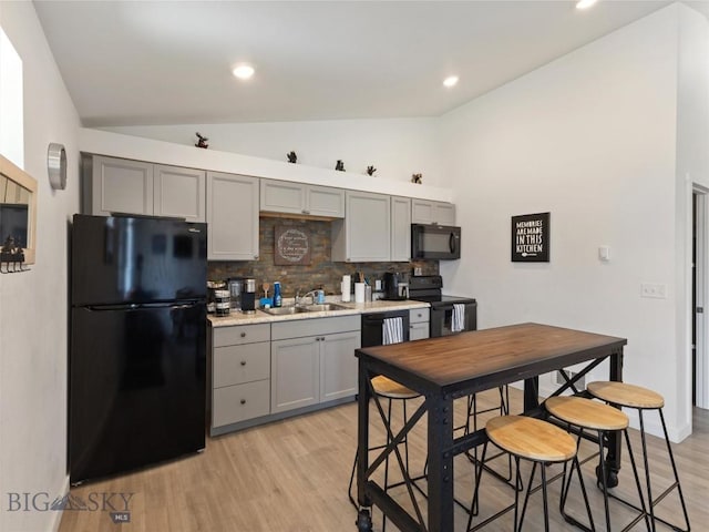 407 Brookline St Unit A, Livingston, MT 59047 - kitchen with black appliances, gray cabinets, vaulted ceiling, a sink, and tasteful backsplash