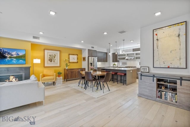 519 E Mendenhall St, Bozeman, MT 59715 - dining room featuring light wood-type flooring, a warm lit fireplace, and recessed lighting