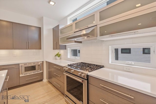 519 E Mendenhall St, Bozeman, MT 59715 - kitchen featuring high end stove, white microwave, decorative backsplash, light wood-style flooring, and light countertops
