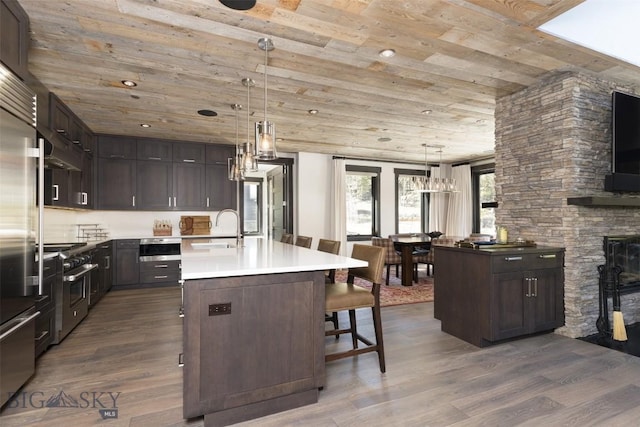 kitchen with a sink, wooden ceiling, dark wood-style flooring, dark brown cabinets, and under cabinet range hood