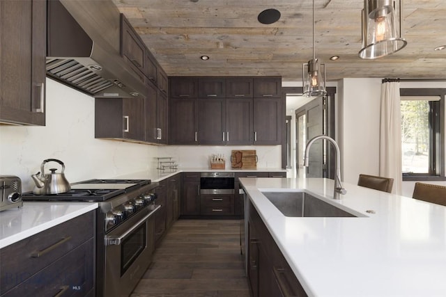 kitchen with wall chimney exhaust hood, high end stainless steel range, a sink, dark wood-style floors, and light countertops