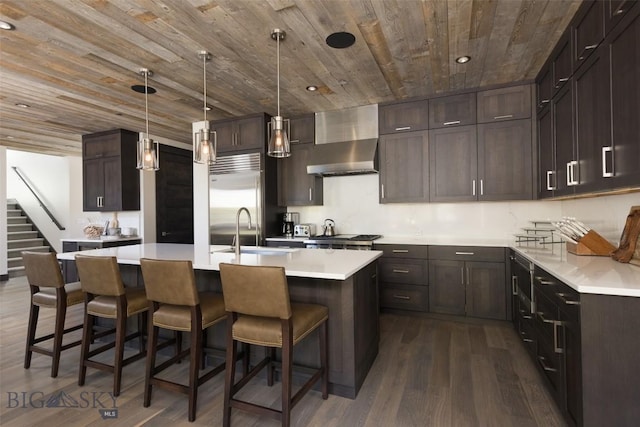 kitchen with wall chimney exhaust hood, a sink, wood ceiling, dark wood-style floors, and dark brown cabinets