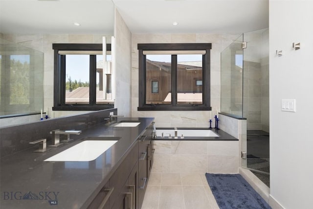 bathroom with a bath, double vanity, tile patterned floors, a shower stall, and recessed lighting