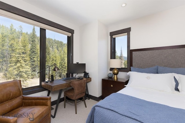 bedroom featuring carpet, an office area, multiple windows, and baseboards