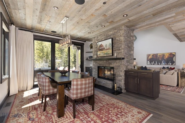 dining room featuring wooden ceiling, dark wood-style floors, and a stone fireplace