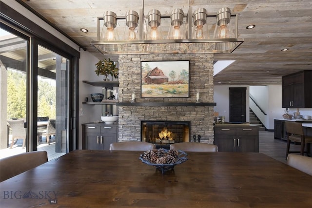 dining space featuring a stone fireplace, stairway, and wood finished floors