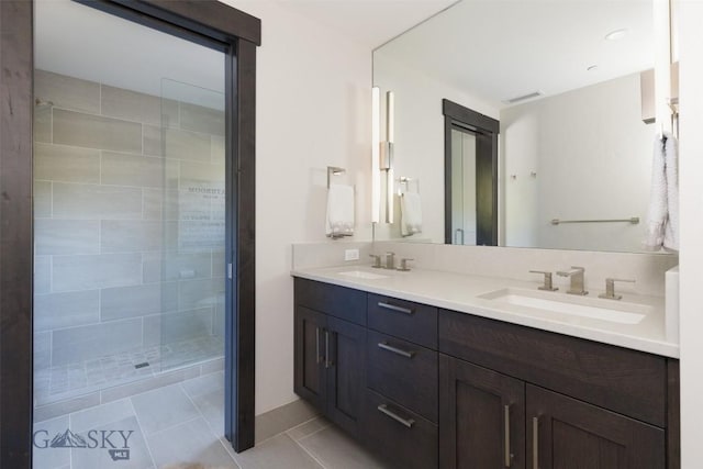 bathroom with double vanity, a tile shower, and tile patterned floors