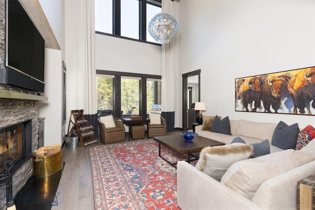 living area with a high ceiling, wood finished floors, and a fireplace
