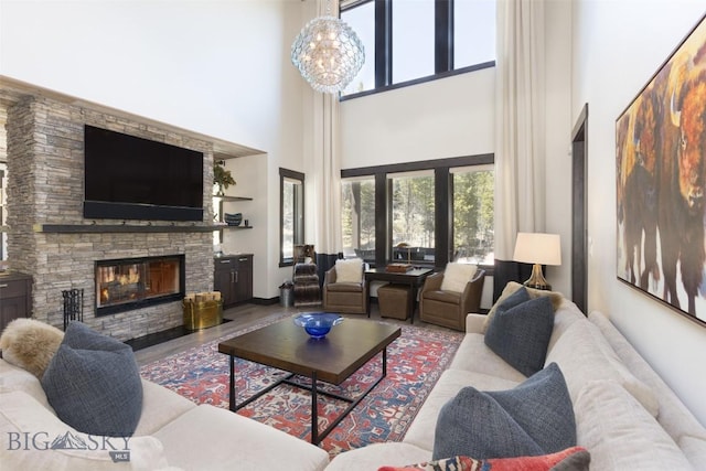 living room with a towering ceiling, a fireplace, wood finished floors, and a chandelier