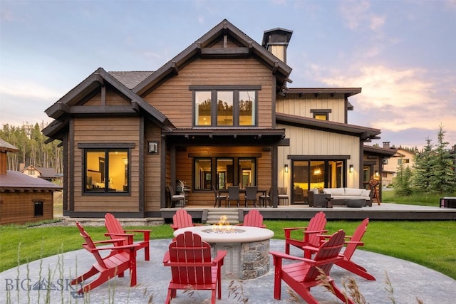 back of property at dusk featuring an outdoor living space with a fire pit, a chimney, and a yard
