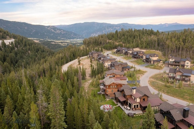view of property location with a heavily wooded area, a mountain backdrop, and nearby suburban area